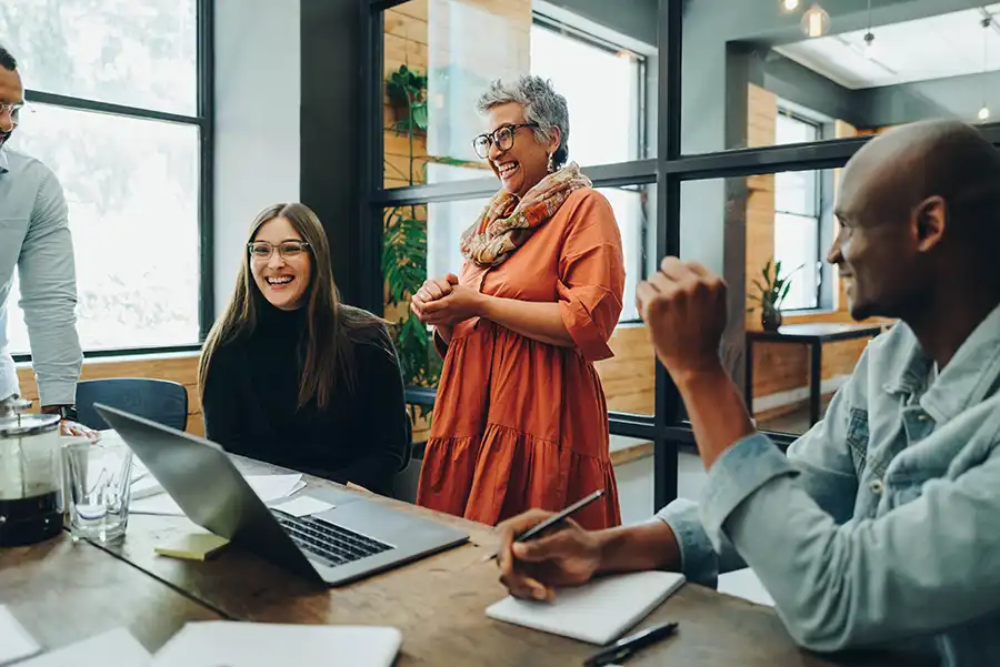 a group of office workers smiling and collaborating with one another